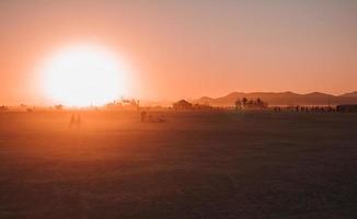 gens en marchant vers le coucher du soleil à une Festival dans le désert à le brûlant homme festival. photo