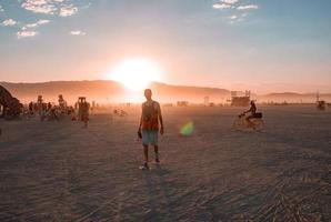 gens en marchant vers le coucher du soleil à une Festival dans le désert à le brûlant homme festival. photo