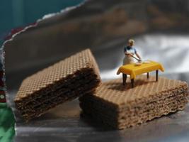 une miniature figure de une femme cuisine sur une Chocolat tranche. photo