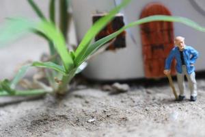 miniature figure de une grand-père qui est attendre dans de face de le maison. photo