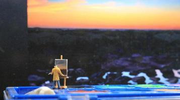 une miniature figure de une peintre La peinture une paysage sur aquarelles. artiste concept. photo