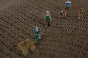 miniature Les figures de Les agriculteurs travail sur jute sacs. concept de agriculture photo. photo