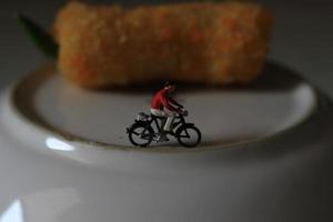 une miniature figure de une cycliste équitation à côté de le gâteau et sur le plaque. photo
