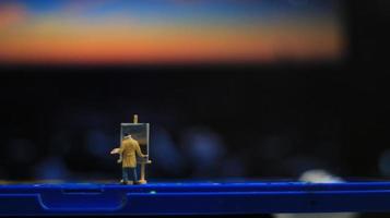 une miniature figure de une peintre La peinture une paysage sur aquarelles. artiste concept. photo