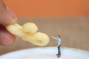 miniature figure de une enfant interagir avec Humain mains donnant aliments. photo