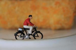 une miniature figure de une cycliste équitation à côté de le gâteau et sur le plaque. photo