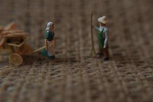 miniature Les figures de Les agriculteurs travail sur jute sacs. concept de agriculture photo. photo