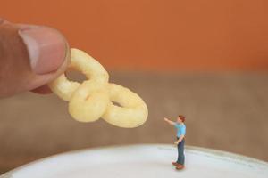 miniature figure de une enfant interagir avec Humain mains donnant aliments. photo