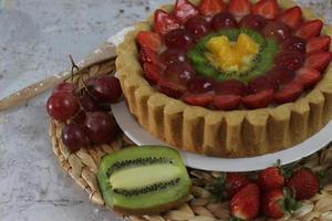 gros fruit tarte avec garnitures de des fraises, raisins, kiwi et ananas. sarriette, sucré et frais. nourriture concept photo. photo