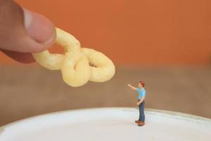 miniature figure de une enfant interagir avec Humain mains donnant aliments. photo