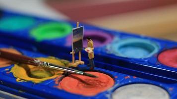 une miniature figure de une peintre La peinture une paysage sur aquarelles. artiste concept. photo