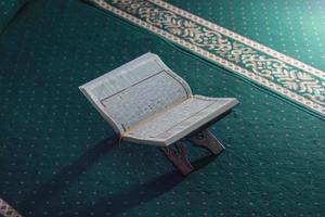 une proche en haut de le saint livre Al Quran sur une vert prière tapis. islamique photo concept.