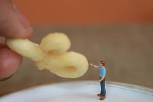 miniature figure de une enfant interagir avec Humain mains donnant aliments. photo