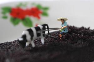 miniature figure de une agriculteur comme si il a été labour une Chocolat éponge gâteau. photo