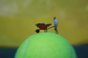 miniature figure de une femelle agriculteur travail le terre avec une lever du soleil Contexte. photo