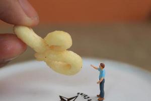 miniature figure de une enfant interagir avec Humain mains donnant aliments. photo