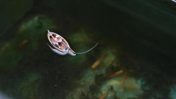 miniature figure de une pêcheur pêche sur une Lac dans une petit bateau. photo