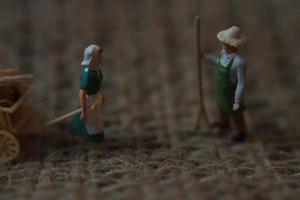 miniature Les figures de Les agriculteurs travail sur jute sacs. concept de agriculture photo. photo