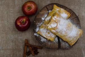 Strudel aux pommes sur l'extrémité en bois d'un arbre avec pommes, cannelle et anis étoilé photo