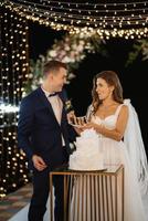 les jeunes mariés coupent et goûtent joyeusement le gâteau de mariage photo