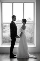 jeune marié dans une noir costume attacher et le la mariée dans une brillant studio photo