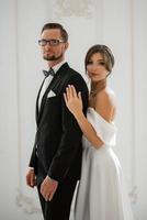 jeune marié dans une noir costume attacher et le la mariée dans une brillant studio photo