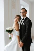 jeune marié dans une noir costume attacher et le la mariée dans une brillant studio photo