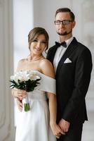 jeune marié dans une noir costume attacher et le la mariée dans une brillant studio photo