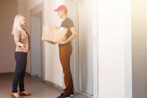 souriant Jeune femme recevoir les courses de livraison homme à appartement photo