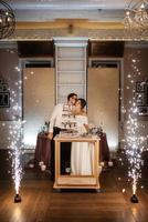 les jeunes mariés coupent et goûtent joyeusement le gâteau de mariage photo