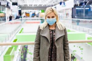 une Jeune femme porte une protecteur masque tandis que achats à le centre commercial. le concept de maladie santé et virus protection. photo