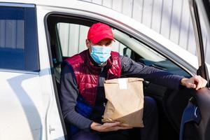 livraison par auto. homme dans protecteur masque et médical gants en portant une papier boîte. livraison un service en dessous de quarantaine, maladie épidémie, coronavirus covid-19 pandémie conditions. photo