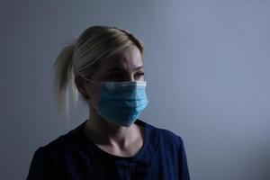 un attrayant Jeune femme porte une papier visage masque à protéger se de le h1n1 virus, isolé sur blanc, avec pièce pour votre texte photo