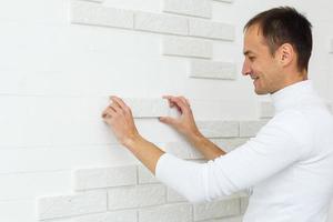 élégant branché blanc céramique tuile avec une chanfreiner sur le cuisine mur. carreleur mains dans le processus de pose blanc rectangulaire carrelage sur salle de bains mur. réparation de appartements et salles de bains. photo