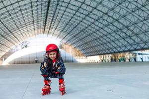 peu mignonne content fille patin à roues alignées dans une gros hangar photo