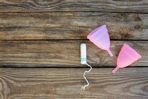 menstruel tasse et tampons sur vieux en bois Contexte. Haut voir. photo