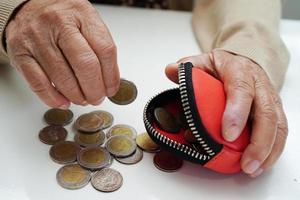 une femme âgée à la retraite comptant des pièces de monnaie et s'inquiète des dépenses mensuelles et du paiement des frais de traitement. photo