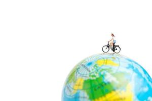Voyageur miniature avec un vélo sur un globe sur fond blanc