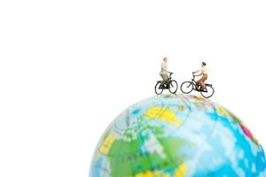 Voyageurs miniatures avec des vélos sur un globe sur fond blanc photo