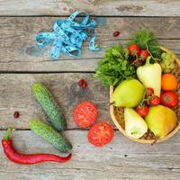 des fruits, des légumes et dans mesure ruban dans régime sur en bois Contexte. Haut voir. photo