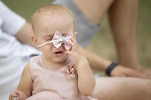 une marrant peu fille supprime une magnifique bijoux de sa diriger. le enfant est un année vieux. photo