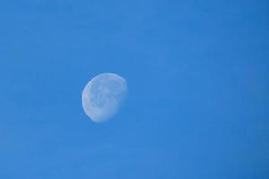 jour plein lune en dessous de le bleu ciel photo