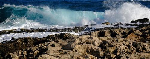 bleu mer vague et blanc mousse et éclaboussure. pierre plage sur île de Malte, non sablonneux plage. été vacances frontière Cadre concept. tropical île vacances toile de fond. touristique Voyage bannière conception modèle. photo