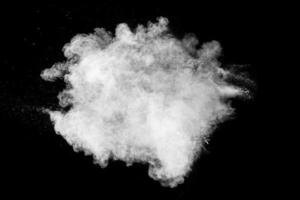 nuage d'explosion de poudre blanche sur fond noir. éclaboussures de particules de poussière blanche. photo