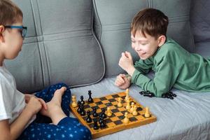 garçons jouer en bois échecs mensonge sur une gris canapé. photo