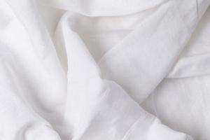 une fragment de froissé blanc en tissu comme une Contexte texture froissée blanc lin ou coton tissu. photo