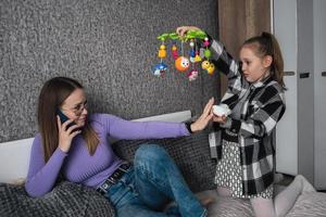 le fille demande sa mère à donner naissance à sa peu frère ou sœur, le mère est parlant sur le téléphone et refuse sa fille. aux femmes réticence à avoir enfants, un enfant dans le famille photo