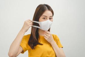 portrait de attractif, jolie asiatique Jeune femme, adolescent portant masque protéger anti virus vaccin COVID-19 [feminine, grippe dans Jaune T-shirt. santé se soucier la prévention isolé sur blanc arrière-plan, copie espace photo