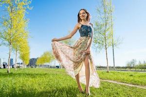 beauté fille en plein air jouit la nature. magnifique modèle dans longue robe ayant amusement photo