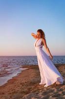 Jeune adulte femme dans une blanc robe sur le plage photo